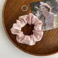 Hellrosa Seiden-Scrunchie mit Perlglanz auf einem dekorativen Vintage-Holztablett - Rosa