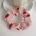 Detalle de coletero de gasa con estampado de fresas rosas sobre mesa blanca y taza - Rosa