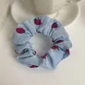 Detalle del coletero de gasa azul claro con estampado de fresas en una taza de té - Azul
