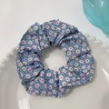 Light blue scrunchie with white daisy floral pattern in a white ceramic dish - Flower