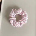 Detailopname van een roze en wit geblokte scrunchie van seersucker textuurstof - Roze