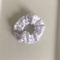 Detail van een lichtpaarse en witte geruite scrunchie met zachte geplooide stoftextuur - Paars