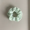 Macro detail of green and white plaid fabric scrunchie showing soft textured pleats - Green