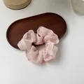 Dettaglio di scrunchie in organza rosa con ricami floreali su vassoio di legno - Ricamo Rosa Rosa