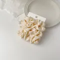 Detail of cream satin scrunchie with silky texture on minimalist white decor - Beige Style