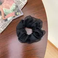 Eleganter schwarzer Organza-Haargummi mit Plissee-Textur auf Holzoberfläche - Einfarbig Schwarz