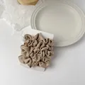 Macro detail of a champagne satin scrunchie with silk-like texture on a white display card - Khaki Style