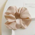 Vue détaillée du chouchou en satin champagne élégant avec des plis de tissu doux - Abricot
