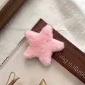 Detail einer rosa flauschigen Stern-Haarklammer auf Zeitschriften mit weicher Textur - Rosa