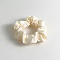 Elegant cream satin scrunchie with a soft glossy finish and pleated design for hair - Off White