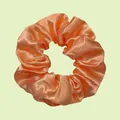 Elastic orange satin scrunchie with soft pleated texture on light green background - Orange Red