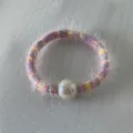 Détail de l'élastique à cheveux rayé arc-en-ciel avec une grande perle blanche nacrée - Bloc De Couleur Rose Arc-en-ciel