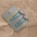 Paar lichtblauwe hartvormige haarclips op displaykaart met een Y2K-esthetiek - Blauw Hart BB Clip