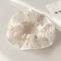 Detailaufnahme eines cremefarbenen Netz-Haargummis mit orangefarbenen Schleifen und Punkten - Beige