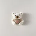 Dettaglio di orsetto di peluche crema con maglione marrone e ricamo a cuore rosa - Stile Spilla Posteriore / Orsetto con Maglione Marrone