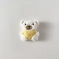 Dettaglio di un orsetto di peluche bianco con un gilet giallo a maglia e cuore ricamato - Stile Spilla Posteriore / Orsetto con Maglione Giallo