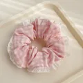 Gros plan d'un chouchou à carreaux roses avec bordure en dentelle blanche sur plateau - Rose à Carreaux
