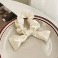 Elegante coletero de satén crema con lazo presentado en un plato de cerámica - Blanco Roto