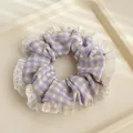 Gros plan d'un chouchou à carreaux violets avec bordure en dentelle blanche délicate - Plaid violet
