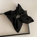 Détail macro du chouchou en soie noire avec broderie de petits nœuds et texture élégante - Style Foulard Carré Nœud Noir