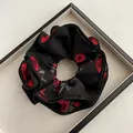 Dettaglio di un elastico per capelli nero con rose rosse vintage e motivi a foglie - Scrunchie con Volant a Doppio Strato