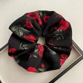 Dettaglio ravvicinato di un grande elastico per capelli in raso nero con rose rosse - Stile Elastico