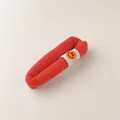 Close-up of a red fabric hair clip with a smiley face tag and textured material detail - Red