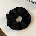 Close-up of black velvet scrunchie with ribbed texture for elegant ponytail styling - Black