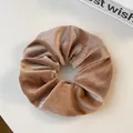 Detail of velvet scrunchie in champagne gold with soft texture and glossy finish - Light Coffee
