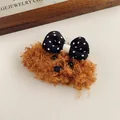 Primer plano de la horquilla de peluche de perro con un lazo de lunares sobre fondo suave - Cachorro color café con lazo de lunares