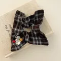 Detail van vintage geruite scrunchie met drie gekleurde kralen op een stoffen boek - Blauw Bruin Ruitpatroon