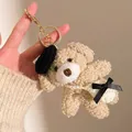 Detail eines flauschigen Teddybär-Anhängers mit Barett und kleiner Umhängetasche - Khaki Bär mit weißem Rucksack
