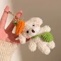 Détail d'un porte-clés chien en peluche blanc avec chapeau carotte et sac au crochet - Ours blanc avec sac à dos vert