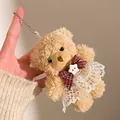 Gros plan d'un pendentif ours en peluche avec robe en dentelle et nœud à carreaux - Ours brun avec robe en dentelle de ballet
