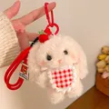 Detail of cute plush bunny keychain with red strawberry accessory and checkered bib - Red Apron Bunny