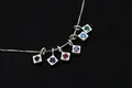 Macro shot of S925 sterling silver charms with multi-colored zircons on a simple box chain - Square-Black