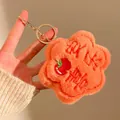 Detail eines weichen orangefarbenen Plüschblumen-Schlüsselanhängers mit Stickerei - Orangerot
