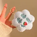 Nahaufnahme des hellblauen Plüsch-Blumen-Schlüsselanhängers mit Erdbeer-Stickerei und Goldring - Blau
