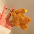 Macro detail of plush brown bear pendant with X-shaped embroidery and golden keychain - Small (With Keychain) / Brown