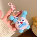 Close-up of pink plush keychain with blue accents and colorful letter beads on hook - Pink