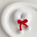 Detail eines weißen Plüsch-Haargummis mit roter Strickschleife und weichen Pompons - Weiß