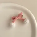 Détail de la pince à cheveux noeud tricoté rose avec pompons blancs et clip bec de canard - Rose