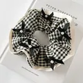 Dettaglio dell'elastico scrunchie a quadretti con pizzo, fiocchi neri e perle - Stile Fiocco Quadretti