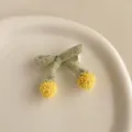 Détail de la pince à cheveux en tricot avec feuilles vertes et pompons jaunes - Vert
