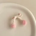 Détail d'une barrette à nœud en tricot rose avec pompons sur un plat en porcelaine - Rose Lotus