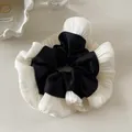 Detail of elegant black satin scrunchie with pleated white lace trim on a minimalist table - Black