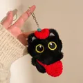 Dettaglio del portachiavi gatto nero di peluche con cappello rosso e occhi ricamati - Stile Zaino Rosso