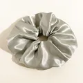 Detail eines übergroßen silbernen Satin-Scrunchie mit glänzender Seidentextur und Falten - Groß / Durchmesser 20cm / Grau