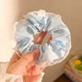 Close-up of blue polka dot scrunchie with lace edges and ribbon bow details - Blue Polka Dot