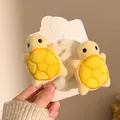 Detail süßer gelber Plüsch-Schildkröten-Haargummis mit weißem Kunstfell auf einer Karte - Gelb